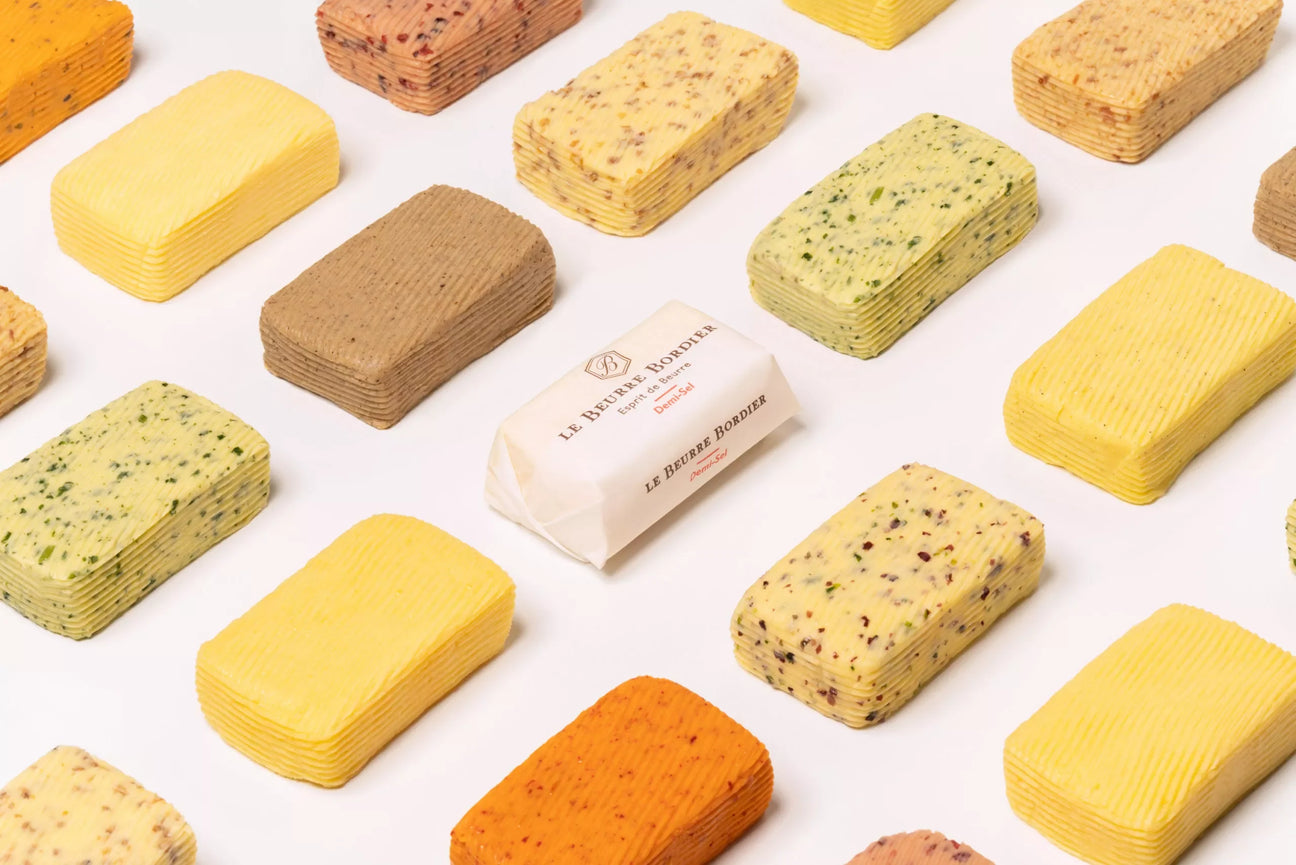 Variety of French artisanal butters, including Maison Bordier, on white background