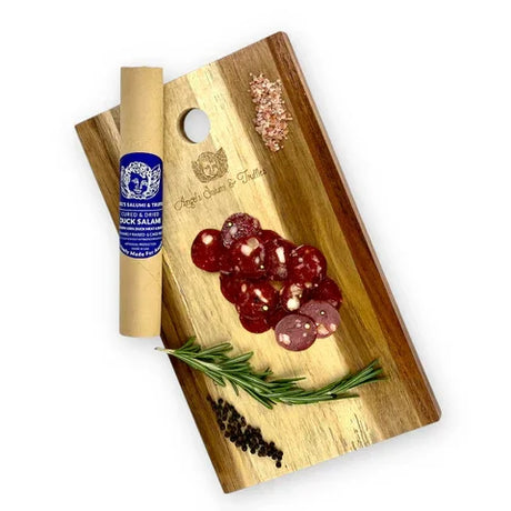 Sliced duck salami on wooden board with rosemary, pink salt, and peppercorns, French charcuterie