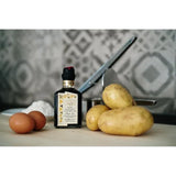 Balsamic vinegar bottle with potatoes and eggs on a kitchen counter