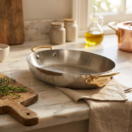 Mauviel stainless steel pan with gold handles on a marble countertop
