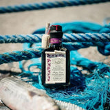 Bottle of balsamic vinegar on a blue fishing net with ropes in the background