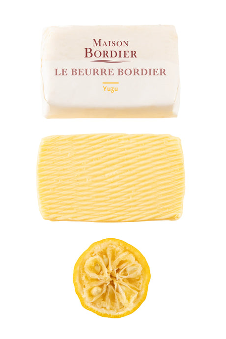 Maison Bordier Yuzu French butter with unwrapped slab and sliced yuzu citrus on white background