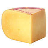 Wedge of French artisan cheese with pale yellow color and natural rind