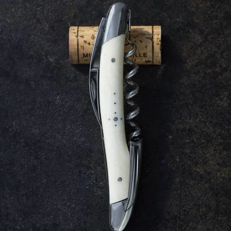 Forge de Laguiole corkscrew with bone handle and cork on dark surface, premium French accessory