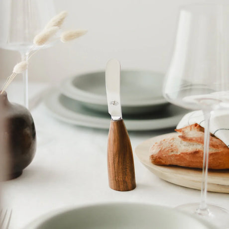 Walnut handle butter knife on elegant table with bread and ceramic plates
