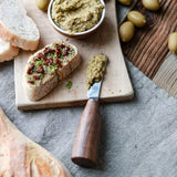 Toasted bread topped with olive tapenade and sun-dried tomatoes on a wooden board.