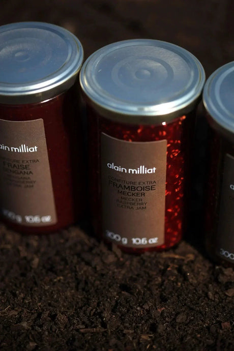 Alain Milliat French raspberry jam jars on dark soil, premium gourmet pantry product