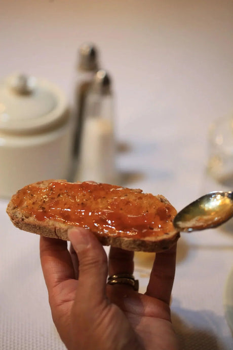Hand spreading French artisan jam on rustic bread with spoon, French Pantry gourmet food