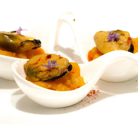Gourmet mussels on mashed potatoes with edible flowers in white porcelain spoons, French artisan cuisine