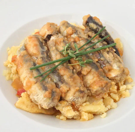 Artisan sardines served over rustic crushed potatoes on a white plate, French Pantry gourmet dish
