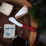 Assorted cheese wedges and a Laguiole cheese knife on a wooden serving board.
