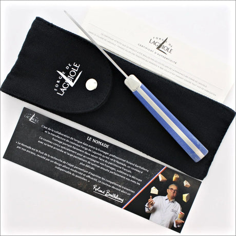 Forge de Laguiole Le Nomade cheese knife with blue handle, black pouch, and authenticity certificate.