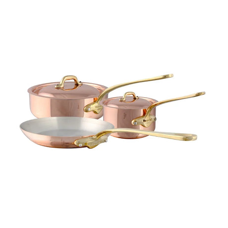 Mauviel copper cookware set with gold-toned handles including a frying pan and two saucepans