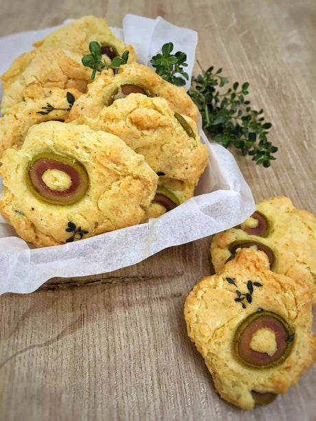 French olive butter cookies with herbs on parchment, wooden table, artisan gourmet snack