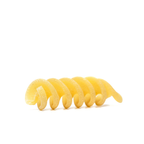 Close-up of a single uncooked fusilli pasta on white background, artisan French Pantry product