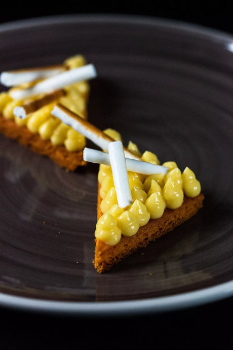 Sable Breton with lemon yuzu cream and meringue sticks on a dark plate, French dessert